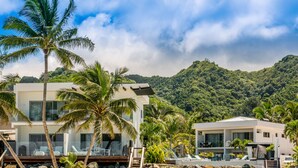 A modern resort with a pool, palm trees, and a mountainous backdrop. - Crystal Blue Lagoon Villas (Rarotonga)