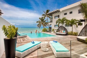 A poolside area with lounge chairs, a small table, and a view of the ocean. - Crystal Blue Lagoon Villas (Rarotonga)