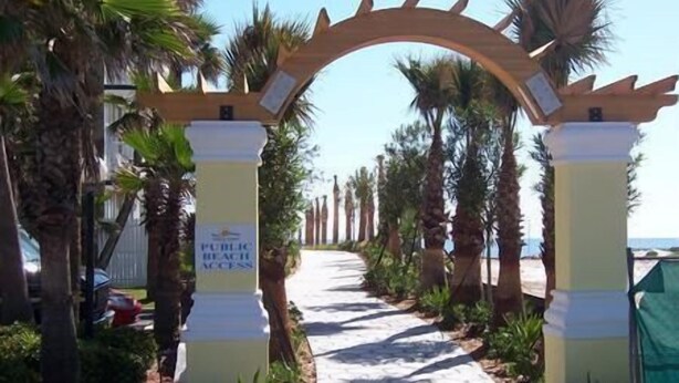 A pathway leading to a beach area with palm trees and a sign indicating public beach access. - Studio 1 Motel (Daytona Beach)
