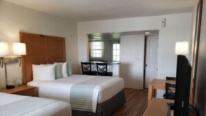 A hotel room with two beds, a desk, a chair, a television, and a mirror. - Studio 1 Motel (Daytona Beach)