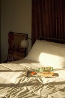 A bed with a pillow and a blanket, a poster on the wall, and a bottle on the bed.