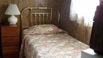 A room with a bed, a dresser, a lamp, and a window with curtains.