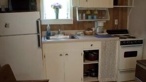 A small kitchen with a refrigerator, stove, sink, and cabinets. - Valley View Motel (Port Townsend)