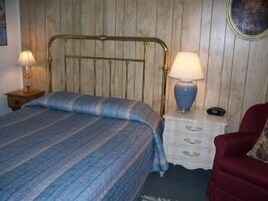 A bed with a striped blanket, a brass headboard, and a bedside table with a lamp.