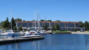 A marina with several boats docked, a building with a red roof, and a clear blue sky. - Royal Harbour Resort (The Blue Mountains)
