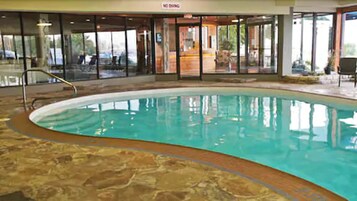 Una piscina interior con suelo de piedra y paredes de vidrio.