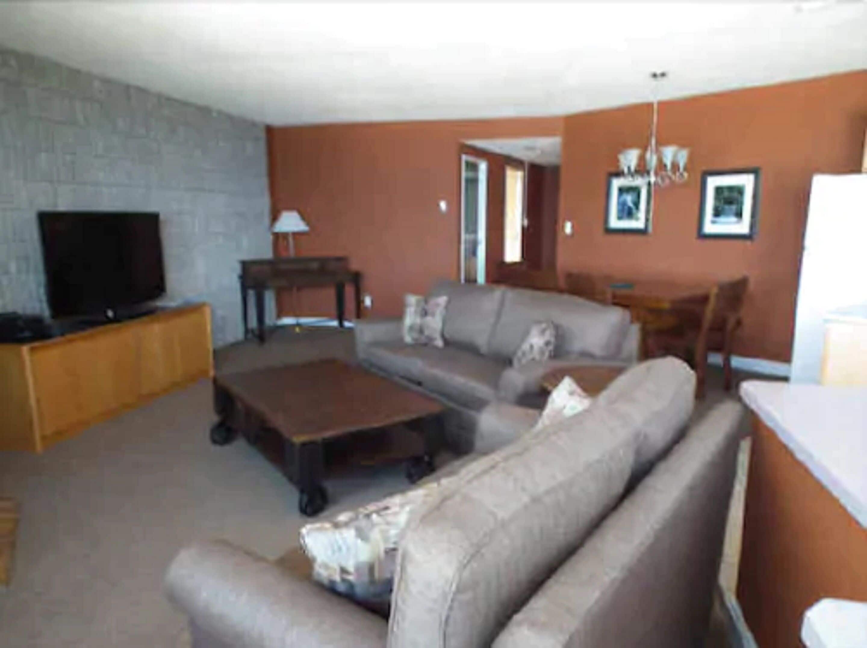 A living room with a sofa, a coffee table, a TV on a stand, and a fireplace.