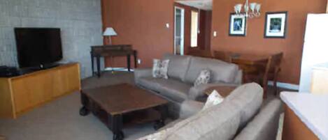 A living room with a sofa, a coffee table, a TV on a stand, and a fireplace.