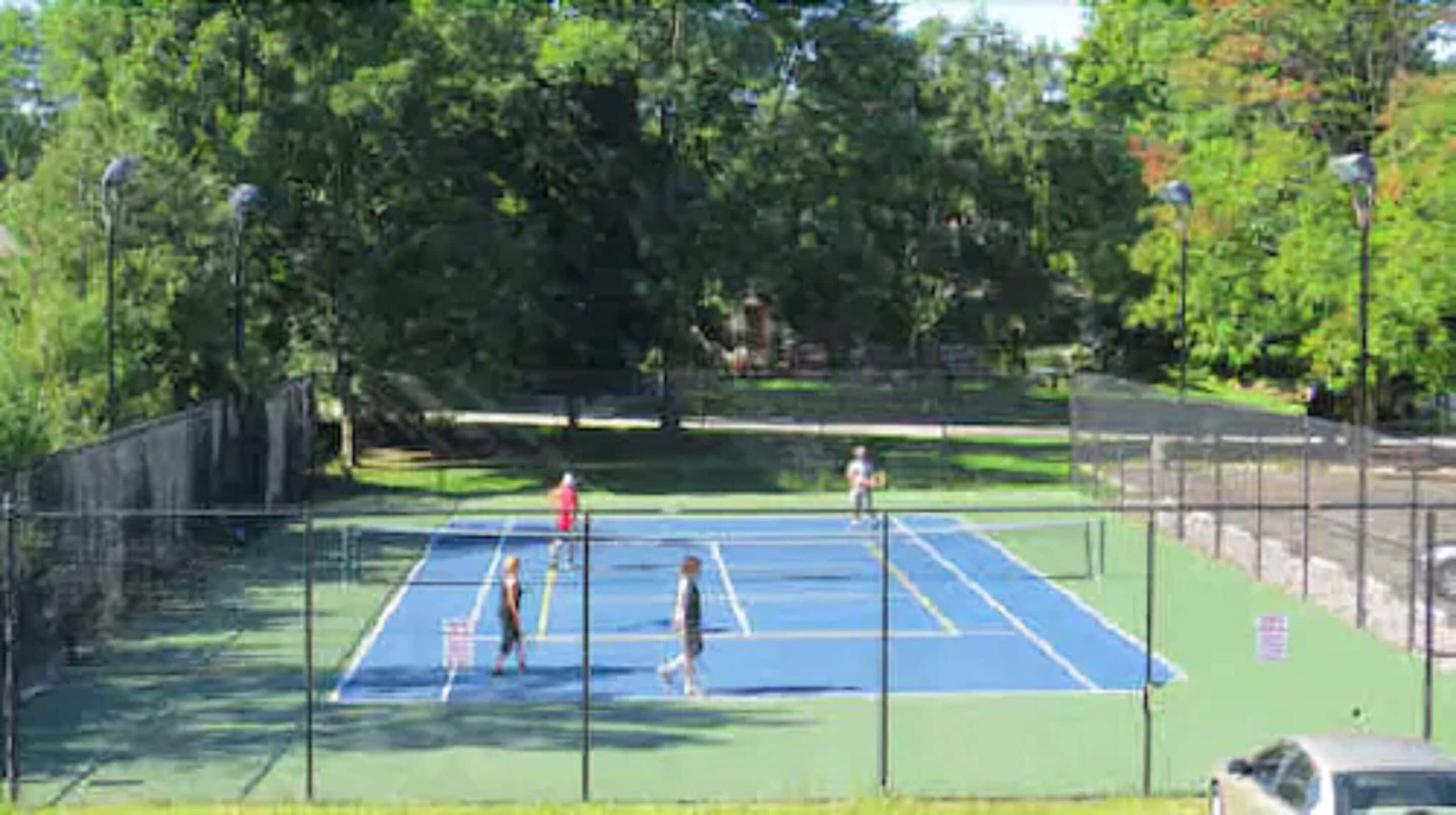 Una cancha de tenis al aire libre rodeada de árboles.