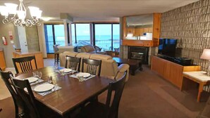 A dining area with a wooden table set for four, a sofa, and a television in the background. - Royal Harbour Resort (The Blue Mountains)