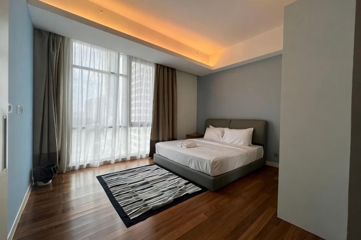 Un dormitorio moderno con cama, ventanas amplias y suelo de madera.
