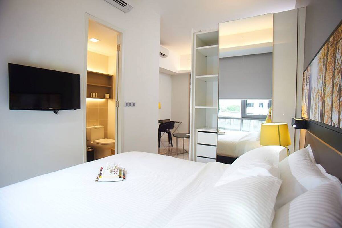 Ein Hotelzimmer mit Bett, einem an der Wand montierten Fernseher, einem Schreibtisch mit Stuhl, einem Kleiderschrank und einem Fenster mit Blick.