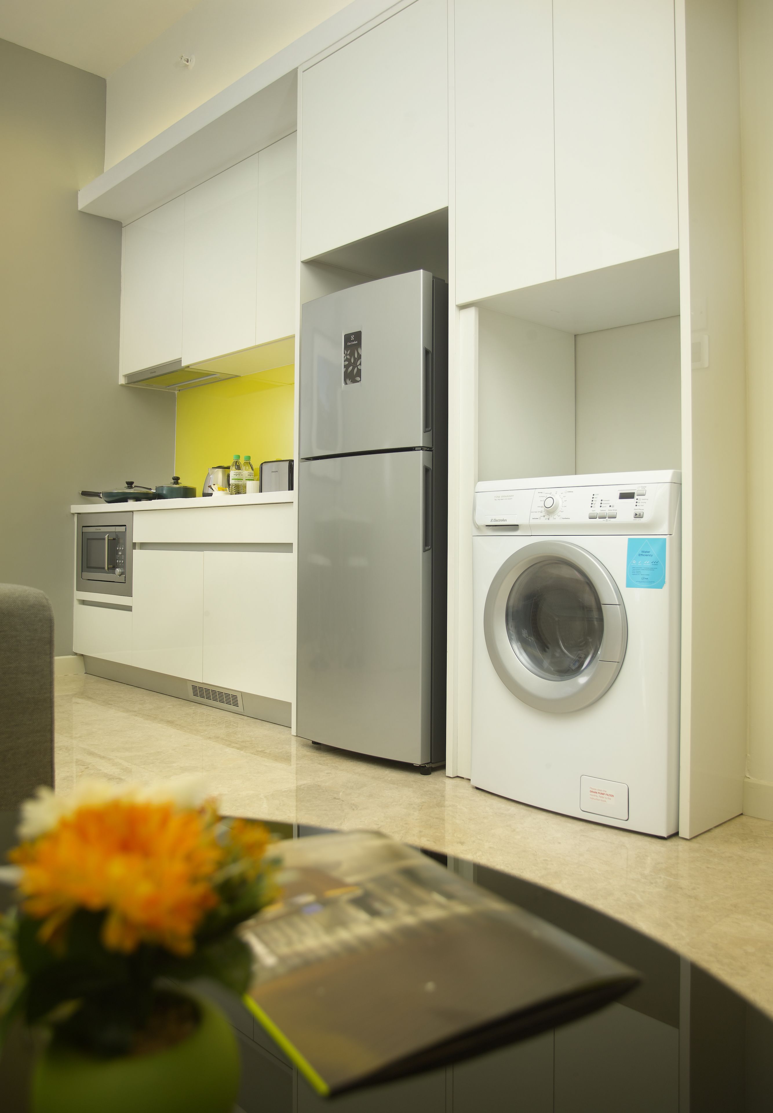 Una cocina compacta con horno integrado, un refrigerador y una lavadora.