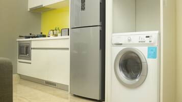Una cocina compacta con horno integrado, un refrigerador y una lavadora.