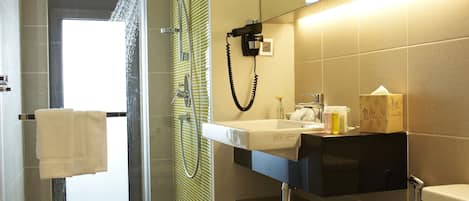 Un baño moderno con ducha de vidrio, inodoro, lavabo y espejo.