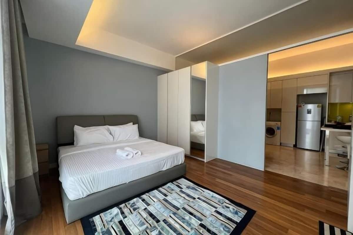 Ein modernes Hotelzimmer mit einem großen Bett, einer kleinen Küchenzeile und einem separaten Badezimmer.
