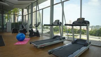 A gym with treadmills, elliptical machines, and a blue exercise ball.