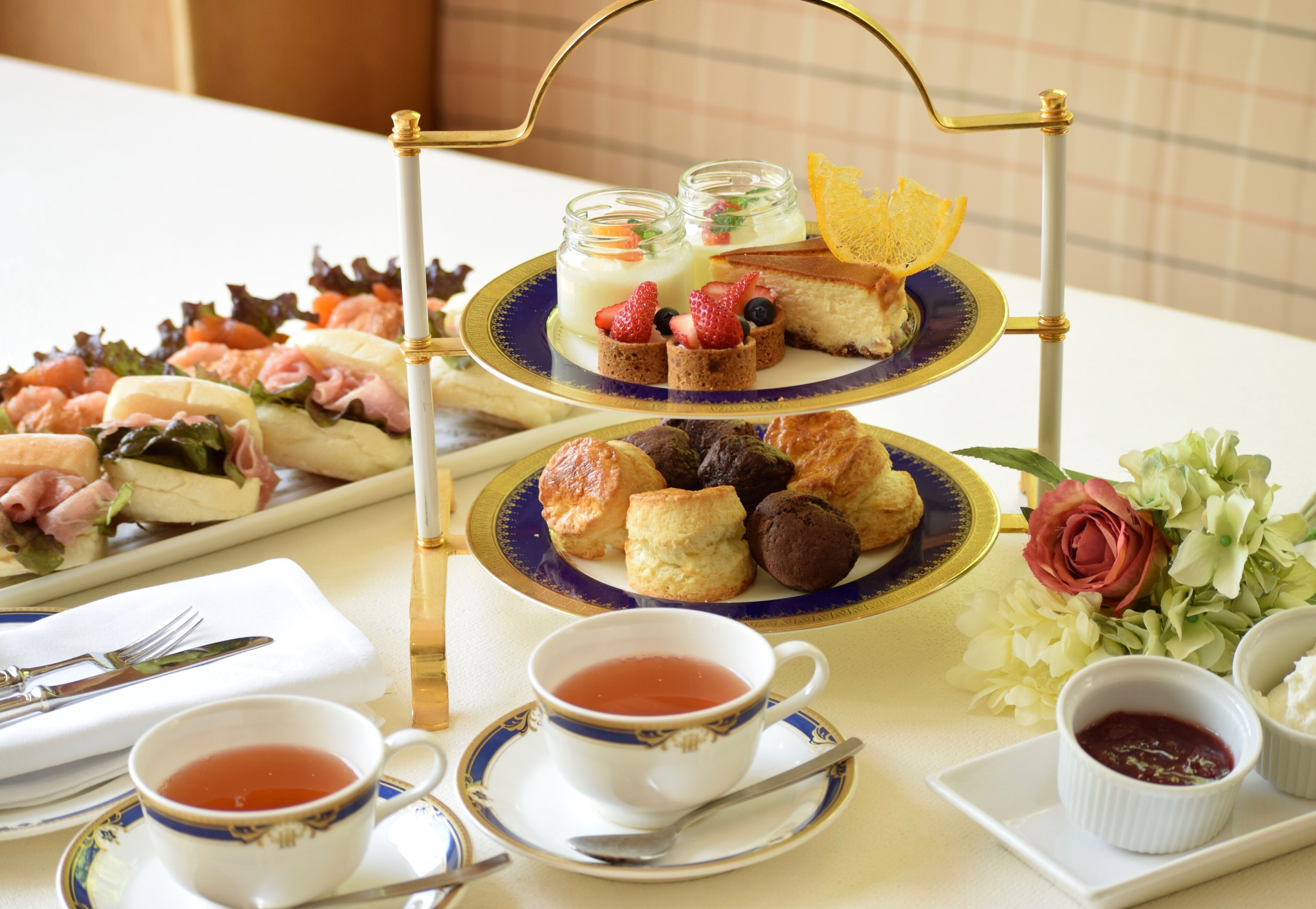 A three-tiered dessert stand with various pastries and a rose centerpiece.