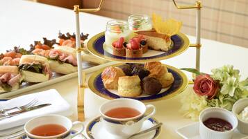 A three-tiered dessert stand with various pastries and a rose centerpiece.