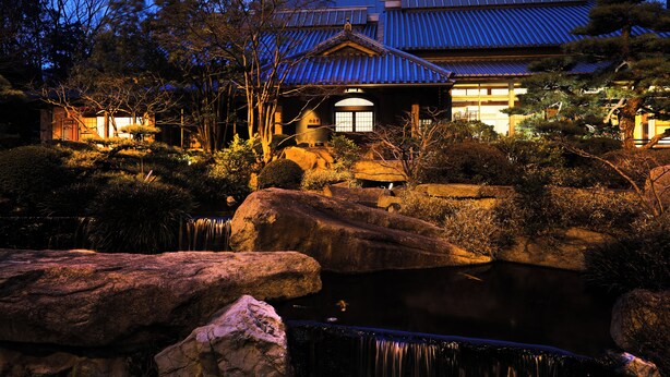 A traditional Japanese building with a tiled roof, surrounded by rocks and a pond. - Imabari Kokusai Hotel (Imabari)