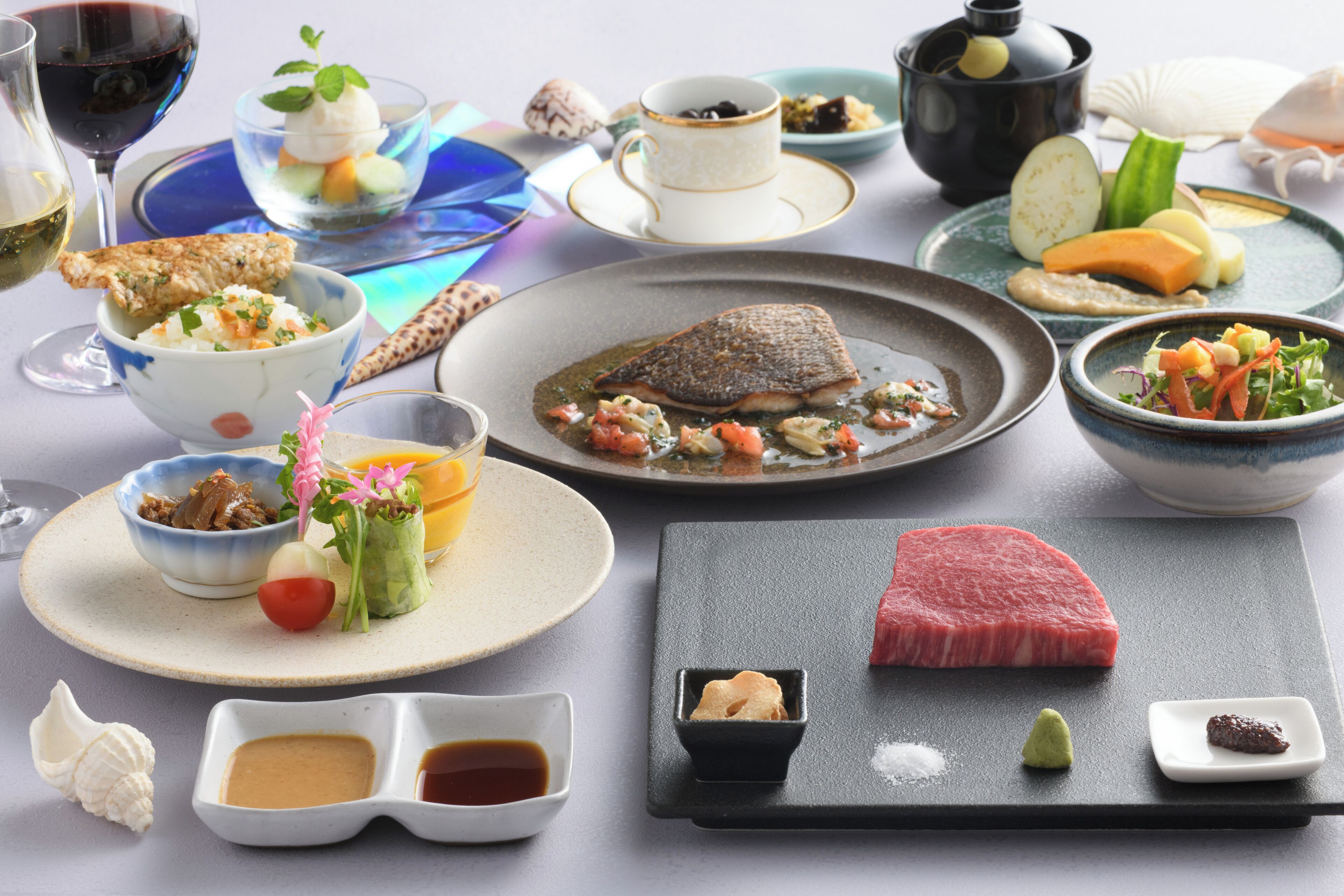 A variety of dishes including sushi, sashimi, and a steak, suggesting a Japanese dining experience.