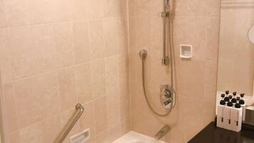 A bathroom with a bathtub, a shower with a handheld showerhead, and a vanity with a black countertop.