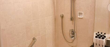 A bathroom with a bathtub, a shower with a handheld showerhead, and a vanity with a black countertop.