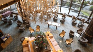 A spacious lounge area with a large chandelier, comfortable seating, and a view of the outdoor garden. - Imabari Kokusai Hotel (Imabari)