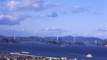 A coastal cityscape with a prominent bridge, dense urban buildings, and a clear sky.