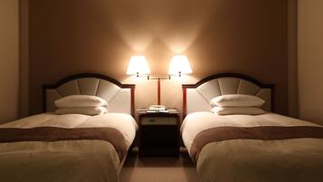 A hotel room with two beds, each with a headboard, a nightstand between them, and two wall-mounted lamps.