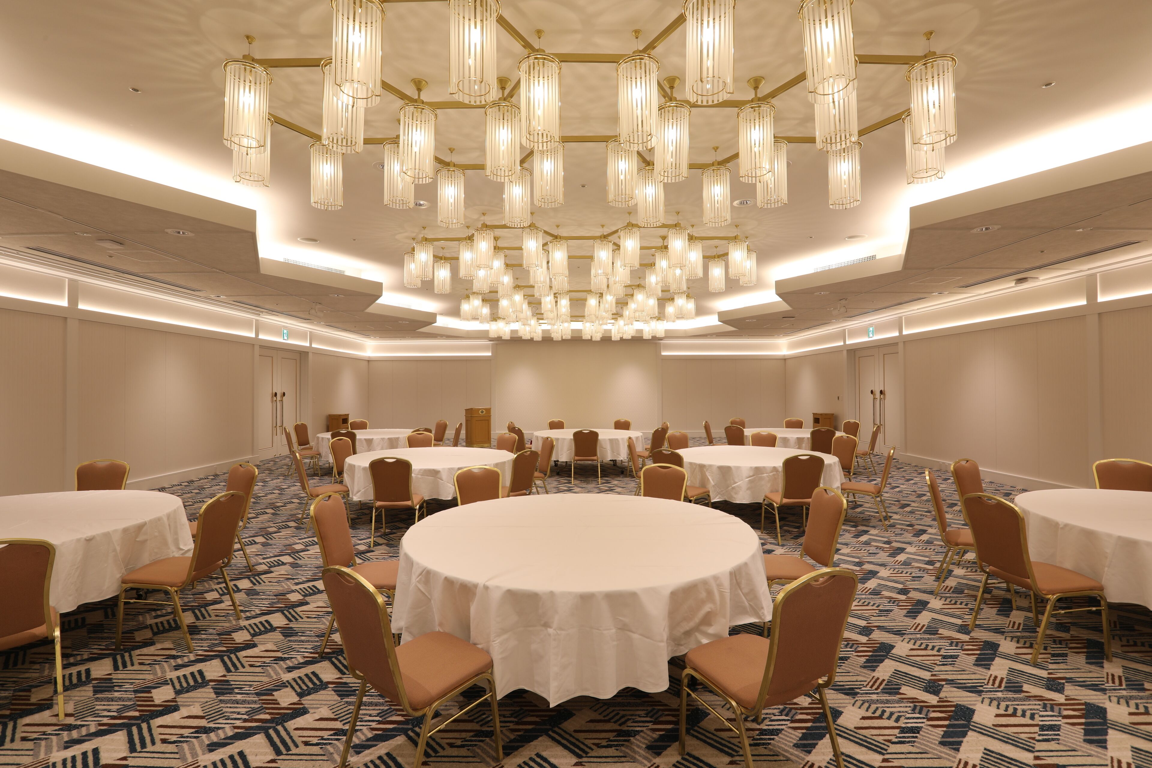 Une salle de conférence dotée de plusieurs tables rondes, de chaises et d’un grand lustre.