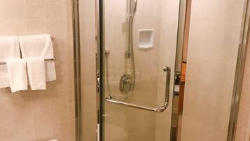 A glass-enclosed shower with a handheld showerhead, a glass door, and a toilet with a control panel.