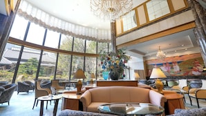 A spacious lobby with a high ceiling, large windows, and a chandelier. - Imabari Kokusai Hotel (Imabari)