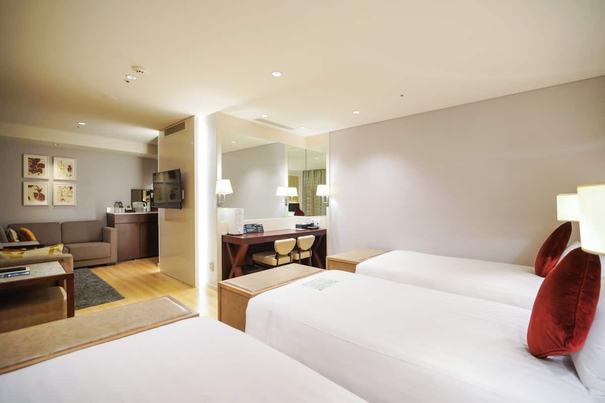 Una habitación de hotel con dos camas, un escritorio, un sofá y un espejo.