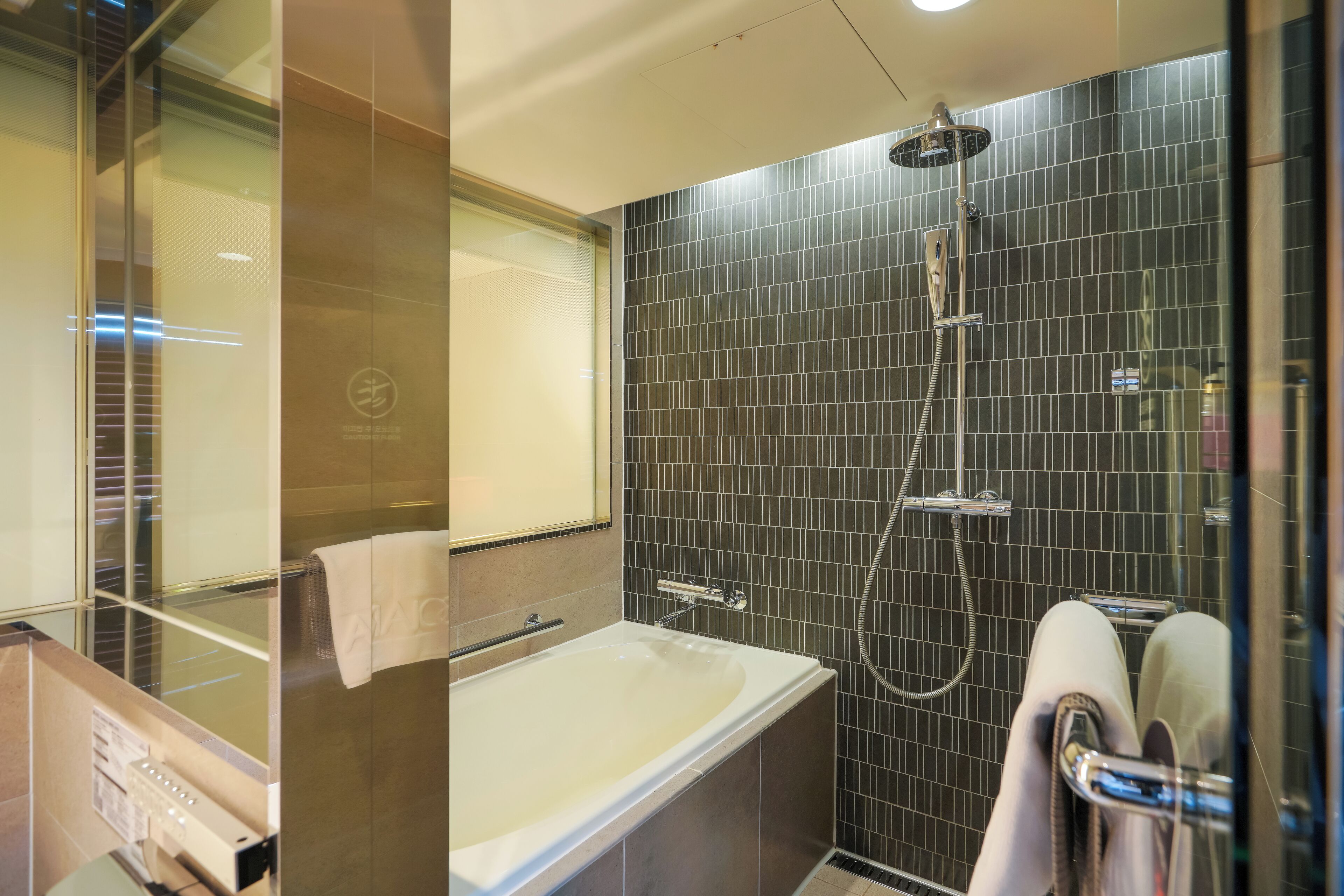 A modern bathroom with a bathtub, a shower, and a glass-enclosed vanity.