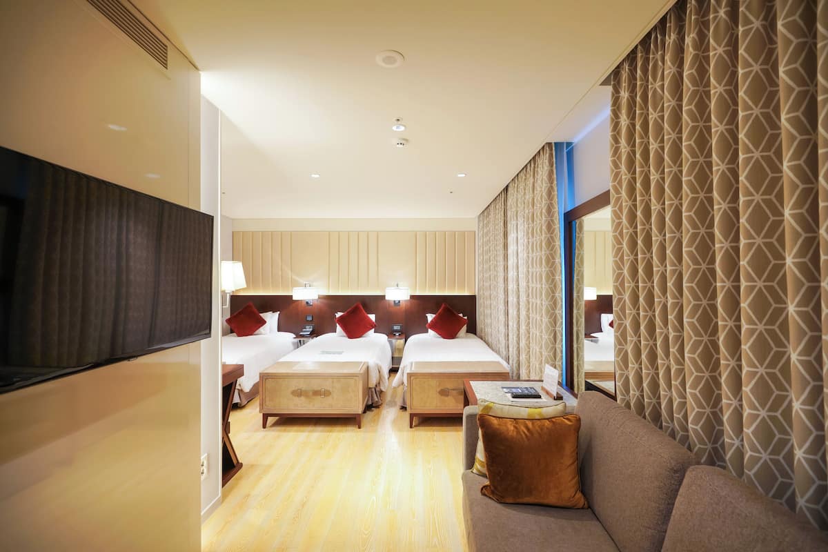 Una habitación de hotel con dos camas, un sofá y un televisor.