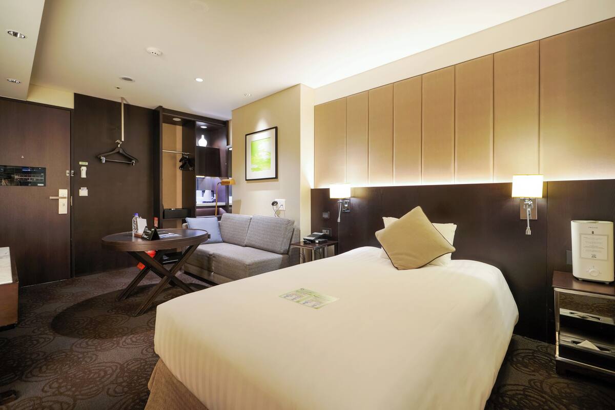 Una habitación de hotel con una cama grande, un sofá, una mesita y un escritorio.