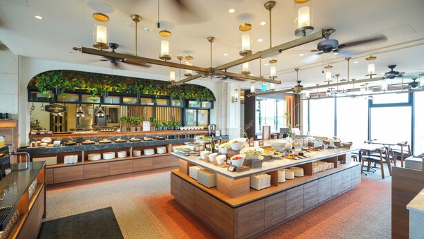Una cocina moderna con una isla central, electrodomésticos integrados y diversos alimentos exhibidos en la encimera.