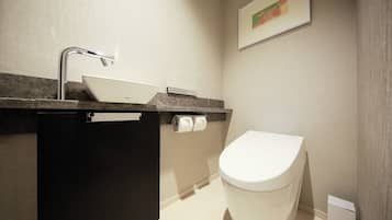 A modern bathroom with a white sink, a black cabinet, a toilet, and a framed picture on the wall.