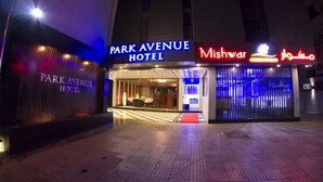 El exterior del Hotel Park Avenue con un letrero de neón rojo que dice Mishwar.