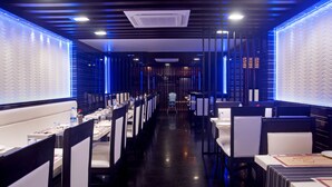 Un restaurante moderno con una barra larga, sillas altas y un pasillo central.