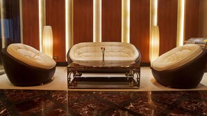 Una habitación lujosa con una bañera central, dos sillones y suelo de mármol.
