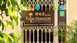 A gated entrance to Palm Mansion Boutique Suites with a sign indicating a 9.5 rating and contact information. - Palm Mansion Boutique Suites (George Town)