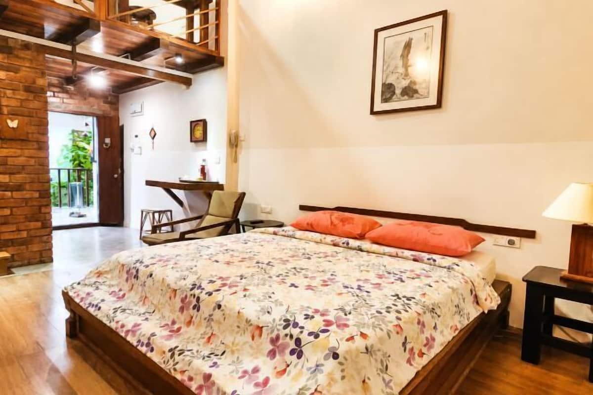 A bedroom with a wooden bed, a desk, a chair, and a balcony view.
