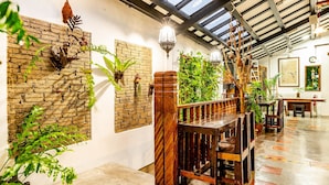 A room with brick walls, wooden furniture, and hanging plants. - Palm Mansion Boutique Suites (George Town)