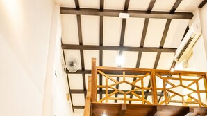 A staircase with wooden railings leading to a loft area with exposed beams and a brick wall. - Palm Mansion Boutique Suites (George Town)
