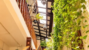 A wooden staircase with a wooden railing, surrounded by greenery and a hanging lantern. - Palm Mansion Boutique Suites (George Town)