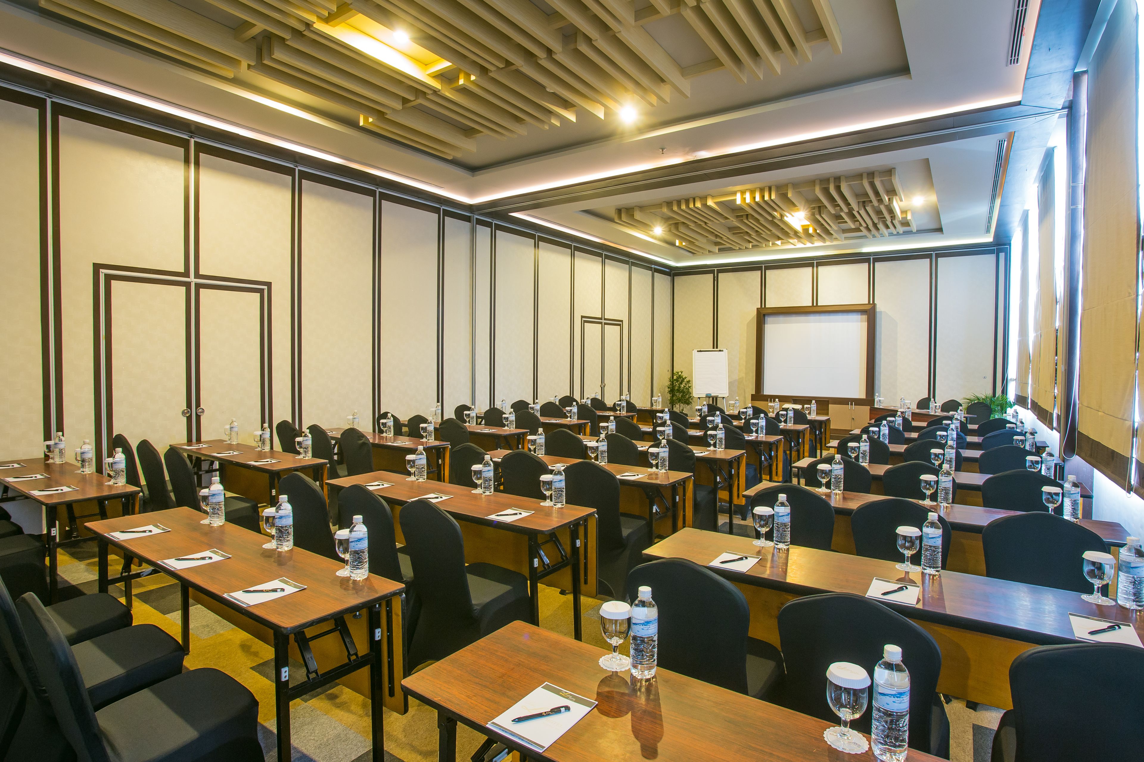 A conference room with multiple tables, chairs, water bottles, and a whiteboard.