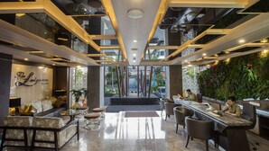 A modern hotel lobby with a reception desk, seating area, and a green wall with plants. - The Lerina Hotel Nusa Dua (Nusa Dua)