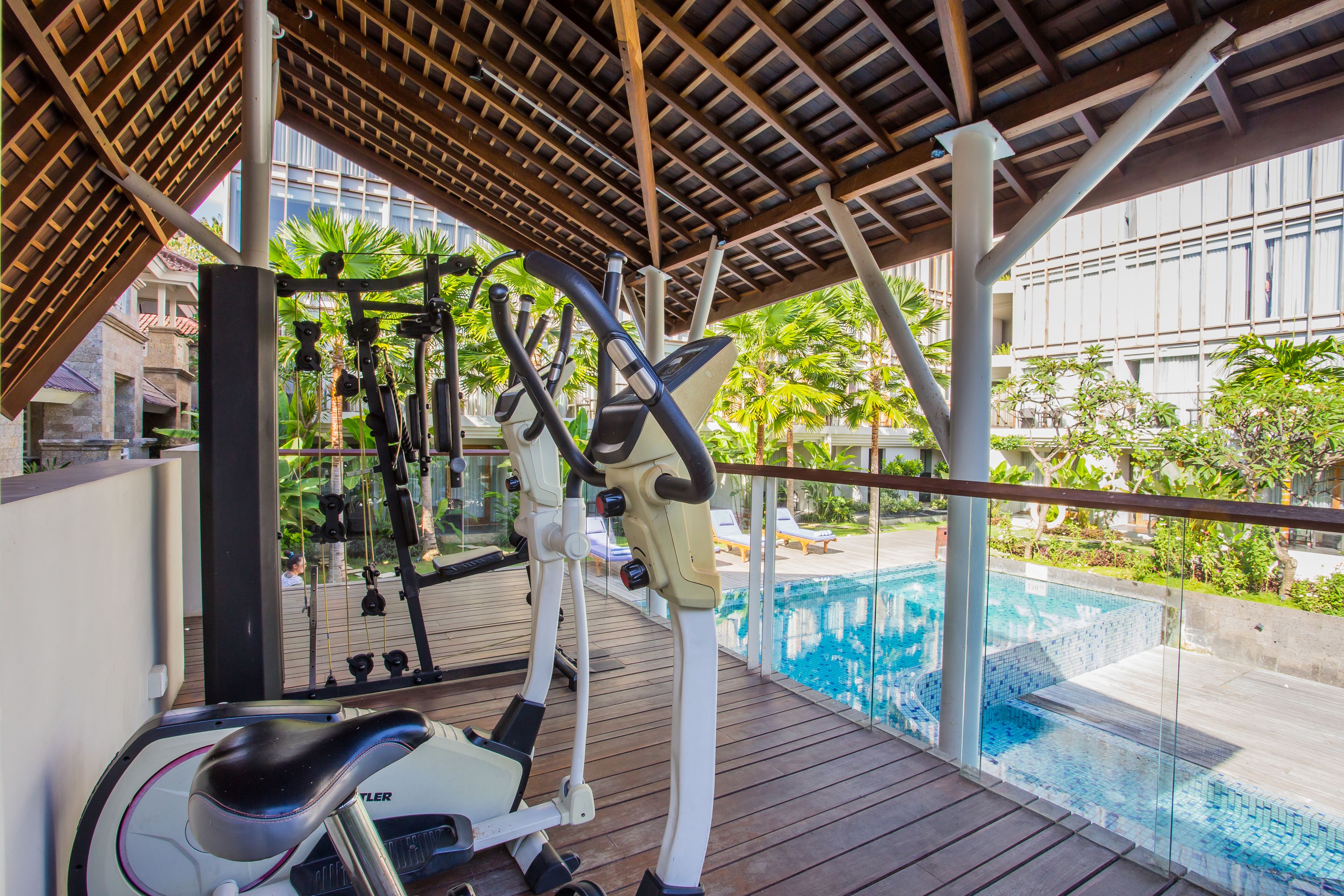 An outdoor gym area with exercise equipment, a wooden deck, and a poolside view.